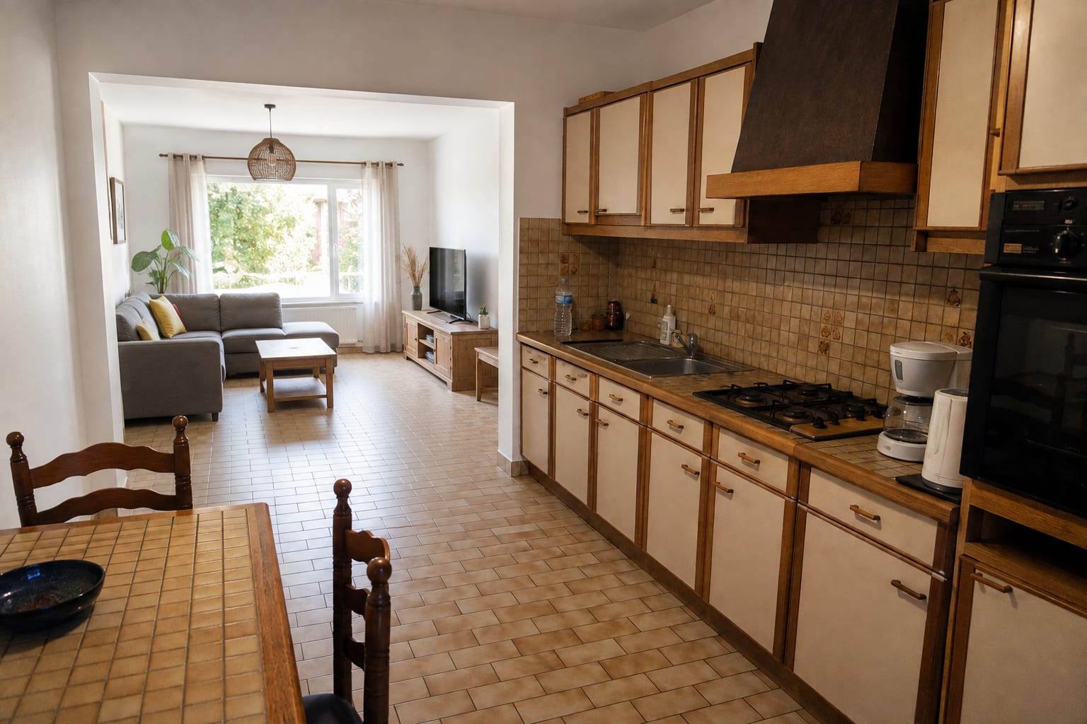 Même pièce après travaux : large ouverture dans le mur portant, linteau intégré et invisible, cuisine et salon communiquant en pleine lumière.