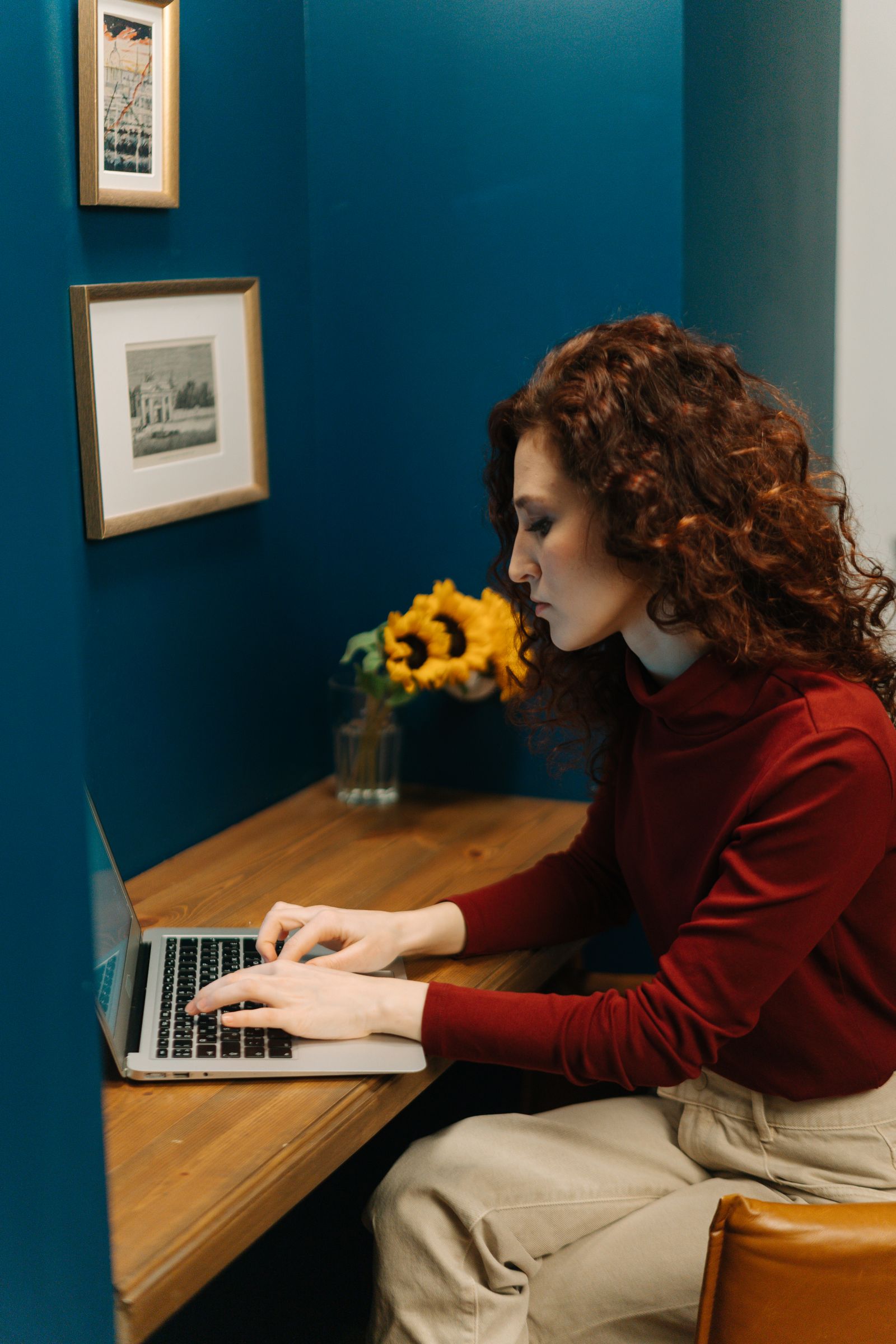 Élise Charlier travaillant à son bureau, dans son atelier aux murs bleus.