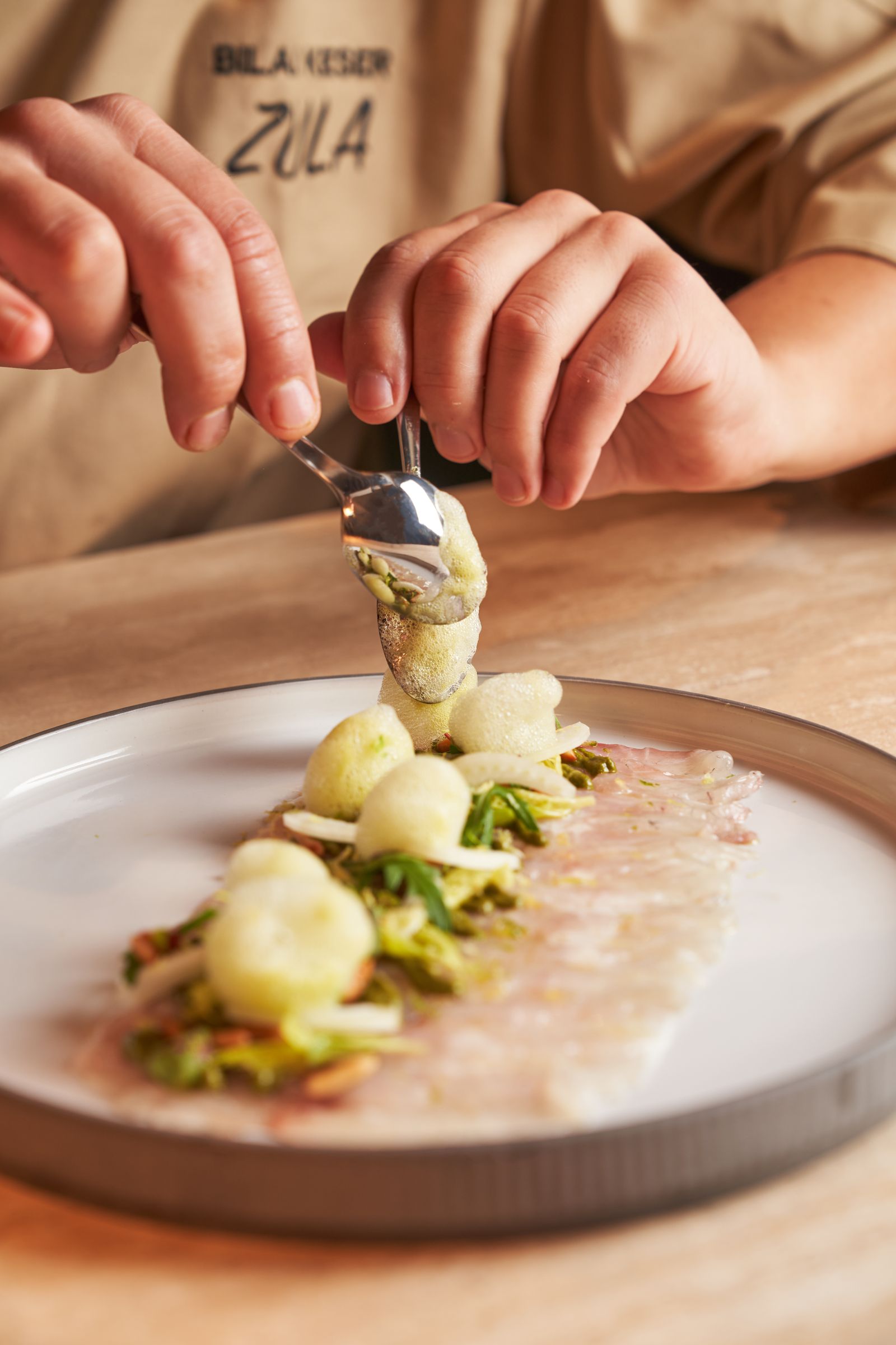 Les mains du chef dressent une assiette au passe.